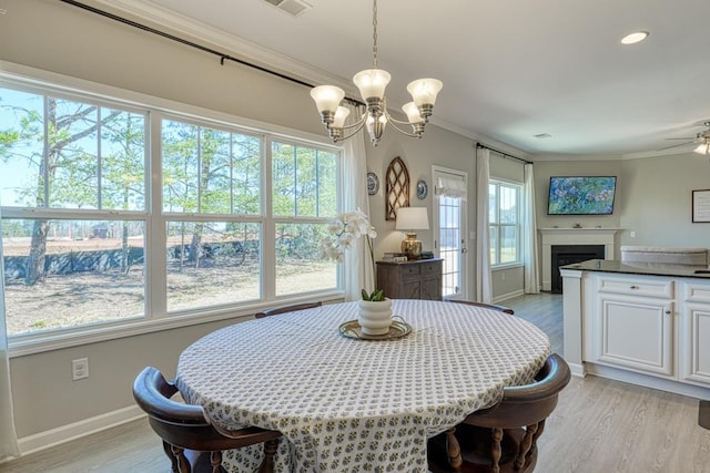 dining room featuring light wood-type flooring, ornamental molding, and ceiling fan with notable chandelier