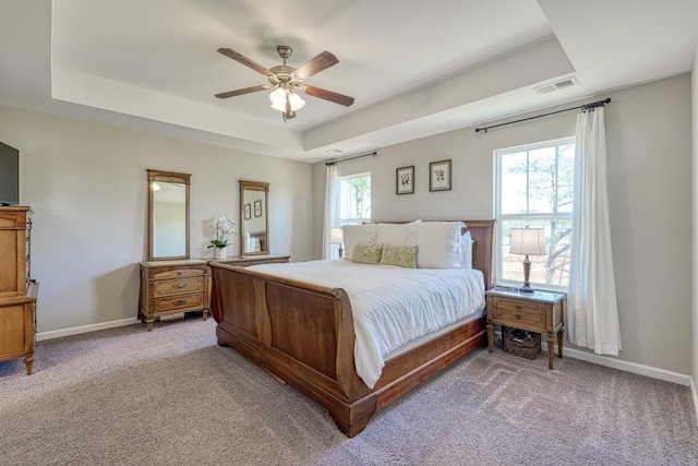 carpeted bedroom with ceiling fan and a raised ceiling