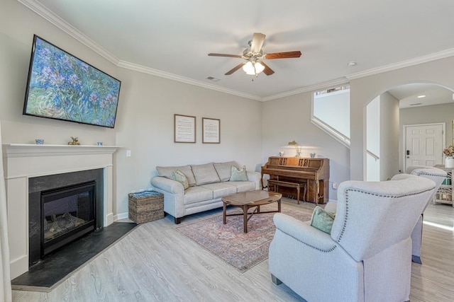 living room with ceiling fan, ornamental molding, and wood-type flooring