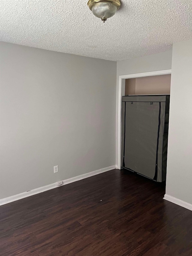 unfurnished bedroom with a textured ceiling, a closet, and dark hardwood / wood-style floors