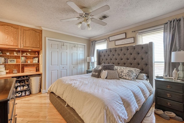 bedroom featuring a closet, light wood-type flooring, a textured ceiling, ceiling fan, and ornamental molding