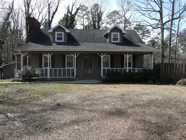 farmhouse inspired home featuring a porch, a front yard, roof with shingles, and fence