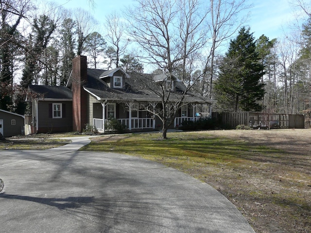 new england style home featuring covered porch and a front yard