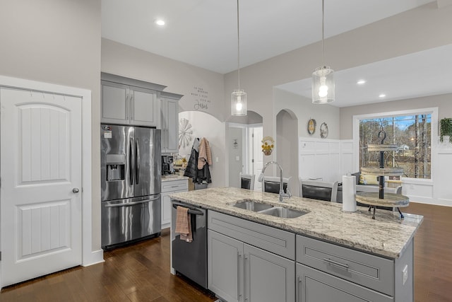 kitchen with sink, gray cabinets, light stone counters, appliances with stainless steel finishes, and pendant lighting