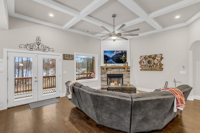 living room featuring coffered ceiling, a stone fireplace, and dark hardwood / wood-style floors