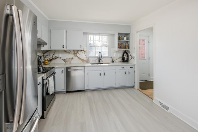 kitchen featuring light hardwood / wood-style flooring, stainless steel appliances, decorative backsplash, ornamental molding, and sink