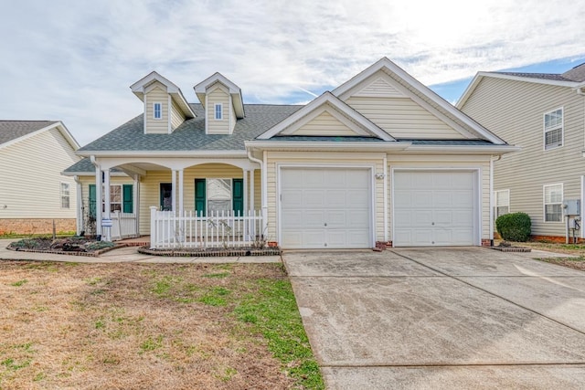 view of front of house featuring covered porch, a garage, and a front lawn