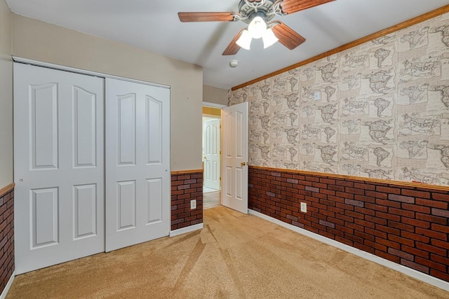 unfurnished bedroom with light carpet, crown molding, a closet, and ceiling fan