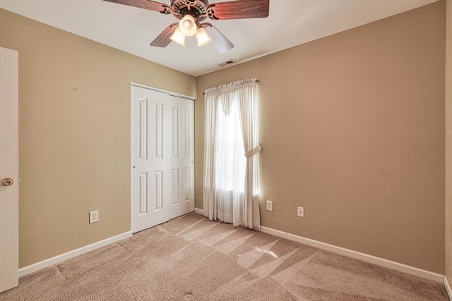 unfurnished bedroom featuring light carpet, ceiling fan, and a closet