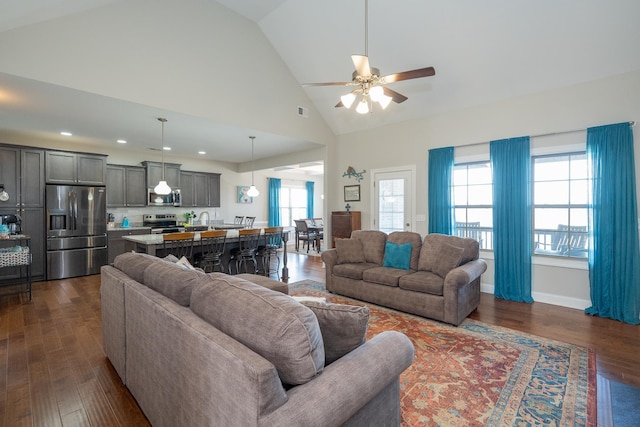 living room with dark hardwood / wood-style flooring, ceiling fan, and high vaulted ceiling