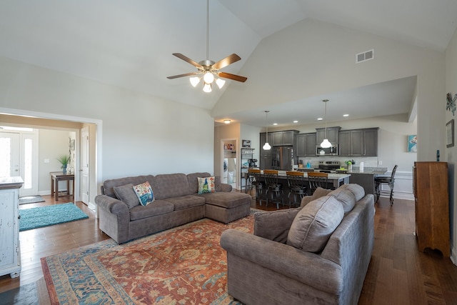 living room with ceiling fan, high vaulted ceiling, and dark wood-type flooring