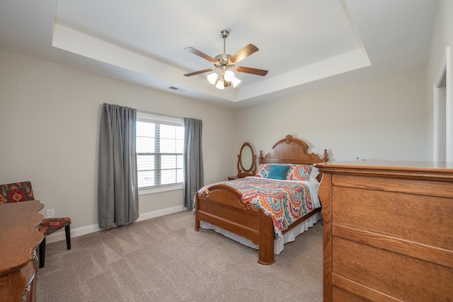 carpeted bedroom featuring a tray ceiling and ceiling fan