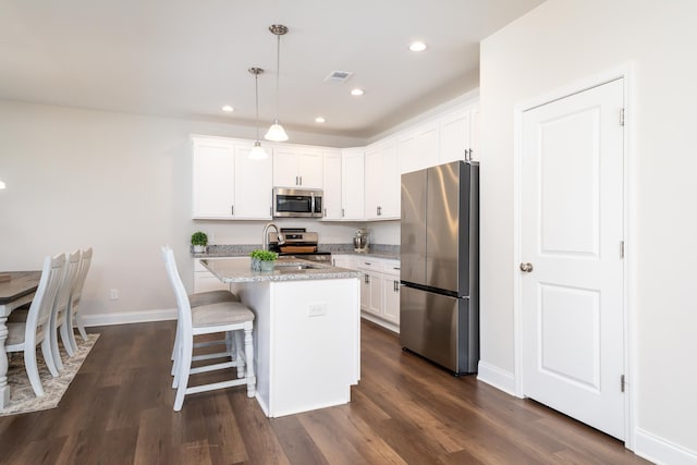 kitchen featuring white cabinets, an island with sink, appliances with stainless steel finishes, and pendant lighting