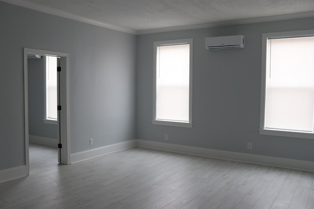 empty room with an AC wall unit, light hardwood / wood-style floors, and plenty of natural light