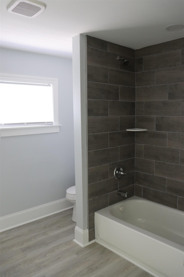 bathroom featuring tiled shower / bath combo, wood-type flooring, and toilet