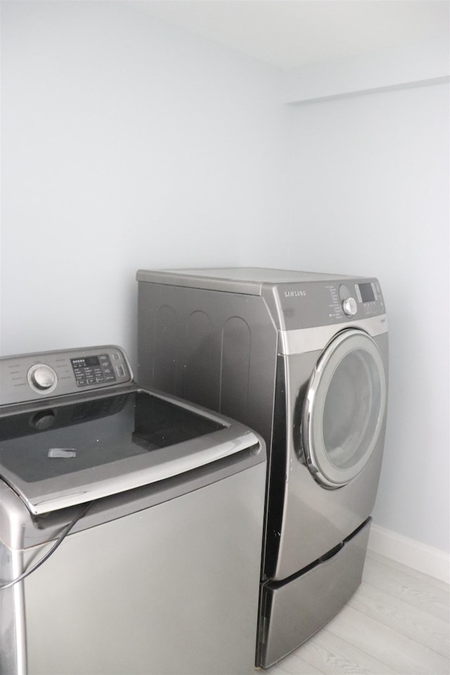 laundry room with independent washer and dryer and light hardwood / wood-style floors