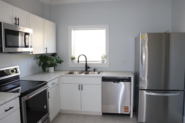 kitchen featuring white cabinets, stainless steel appliances, light stone counters, and sink