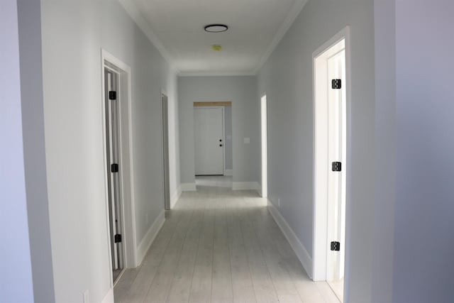 corridor with light wood-type flooring and crown molding