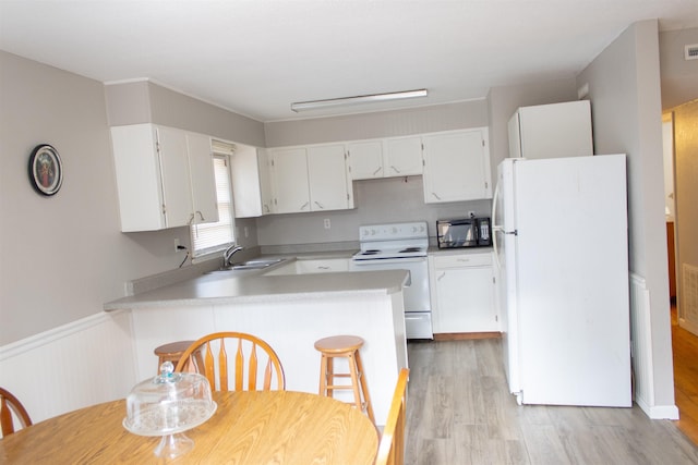 kitchen featuring white appliances, kitchen peninsula, white cabinets, and light hardwood / wood-style floors