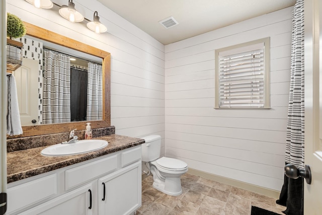 bathroom with vanity, toilet, and wooden walls