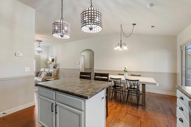 kitchen featuring hanging light fixtures, an inviting chandelier, a kitchen island, and dark hardwood / wood-style floors