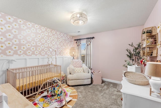 carpeted bedroom with a crib and a textured ceiling