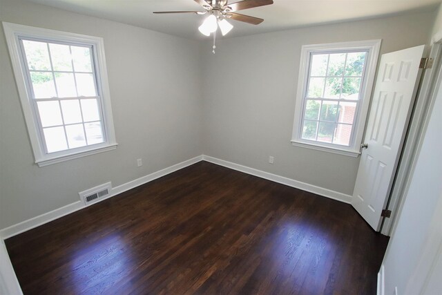 empty room featuring baseboards, ceiling fan, visible vents, and dark wood-style flooring