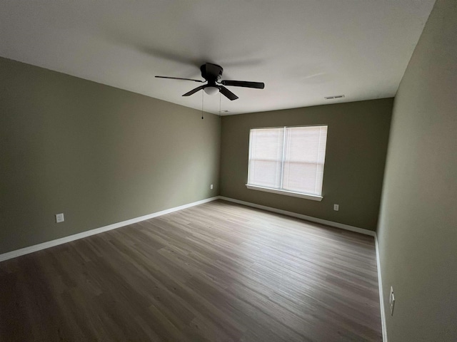 unfurnished room with a ceiling fan, visible vents, baseboards, and wood finished floors