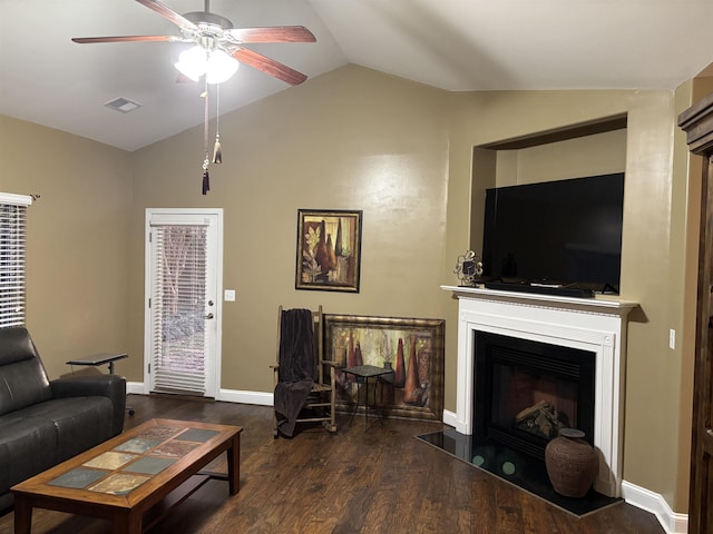 living room featuring lofted ceiling, ceiling fan, dark wood-style flooring, a fireplace with flush hearth, and visible vents