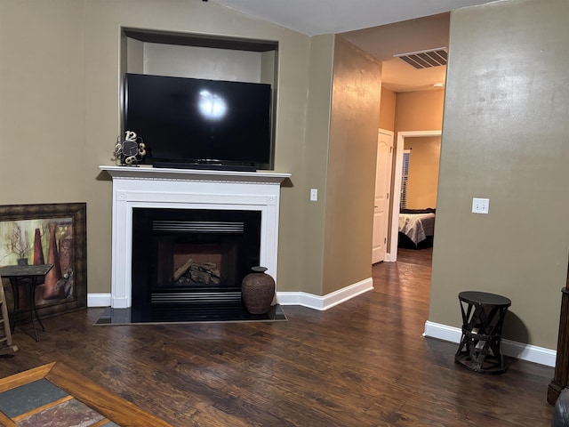 living area featuring lofted ceiling, a fireplace with flush hearth, visible vents, baseboards, and dark wood-style floors