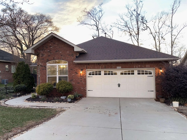 single story home featuring a garage, concrete driveway, brick siding, and roof with shingles