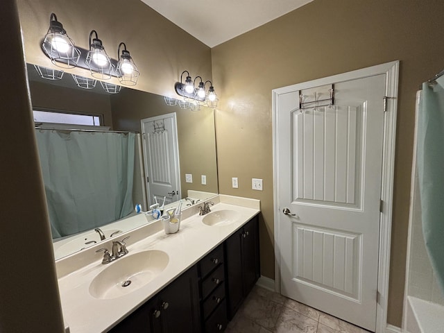 full bath featuring marble finish floor, a sink, and double vanity