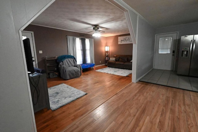 living area featuring ornamental molding, wood finished floors, a ceiling fan, and baseboards