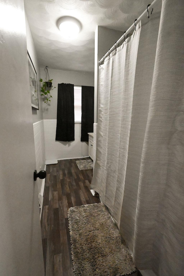 bathroom with curtained shower and wood finished floors