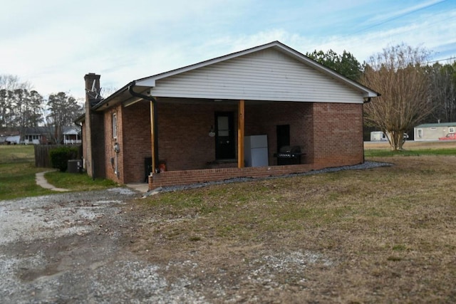 back of property featuring brick siding, a lawn, and a chimney