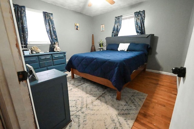 bedroom with a ceiling fan, light wood-type flooring, and baseboards