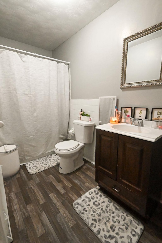 bathroom with toilet, tile walls, wood finished floors, and vanity