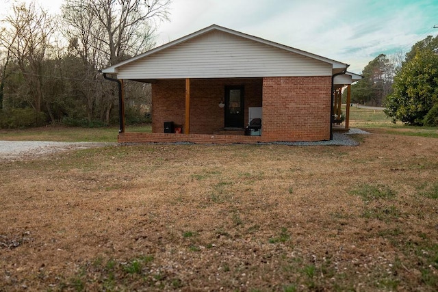 back of property featuring brick siding and a yard