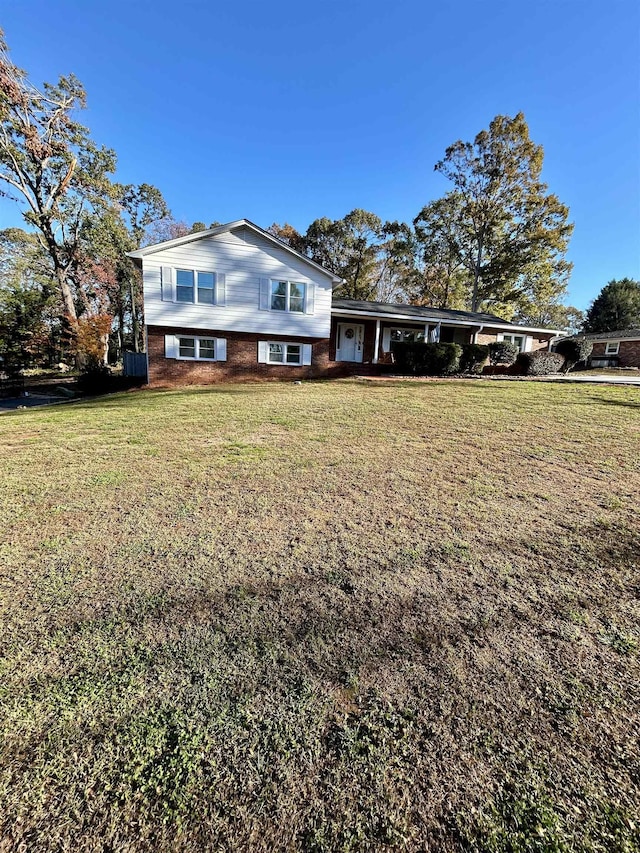 tri-level home with a front lawn, an attached carport, and brick siding