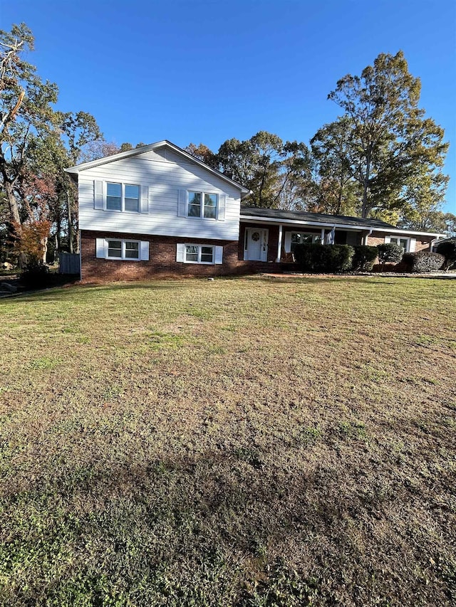 tri-level home featuring a front lawn and brick siding