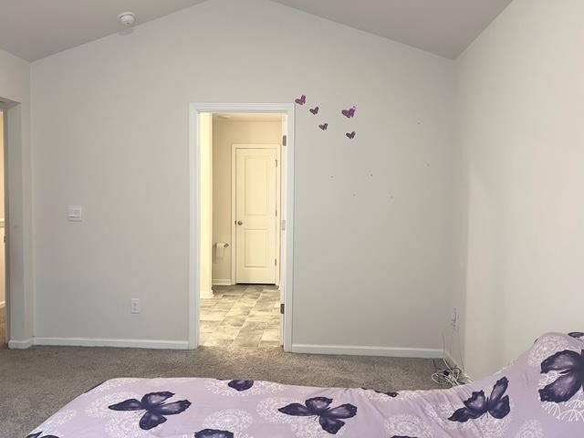 carpeted bedroom with baseboards and vaulted ceiling
