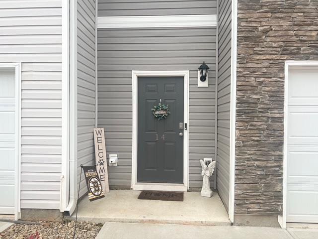 property entrance with a garage and stone siding