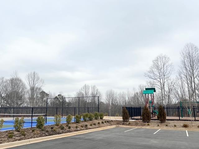 exterior space featuring a tennis court, fence, and playground community