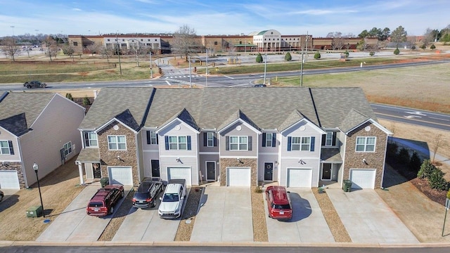 exterior space with a garage, a residential view, stone siding, and driveway