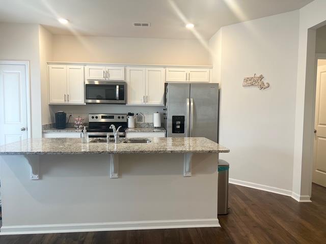 kitchen with appliances with stainless steel finishes, a breakfast bar, visible vents, and white cabinets