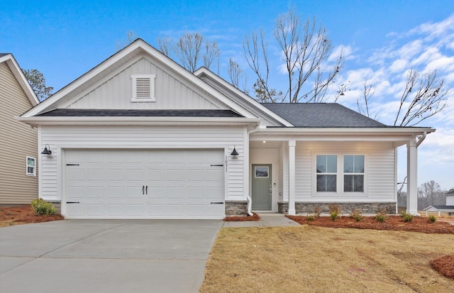 craftsman-style house with a garage, stone siding, concrete driveway, a front lawn, and board and batten siding