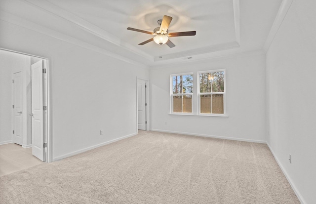 unfurnished room featuring ornamental molding, a tray ceiling, light colored carpet, and baseboards