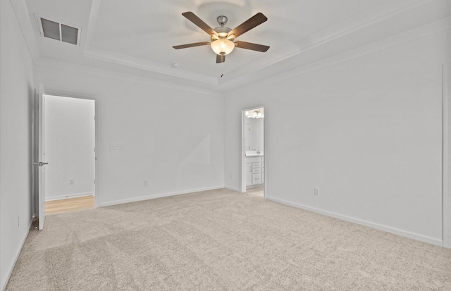 unfurnished room featuring a tray ceiling, crown molding, visible vents, light carpet, and baseboards