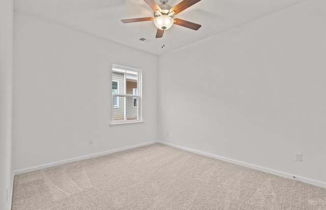 carpeted empty room featuring visible vents, ceiling fan, and baseboards