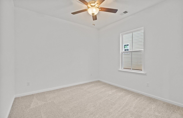 carpeted spare room featuring ceiling fan, visible vents, and baseboards